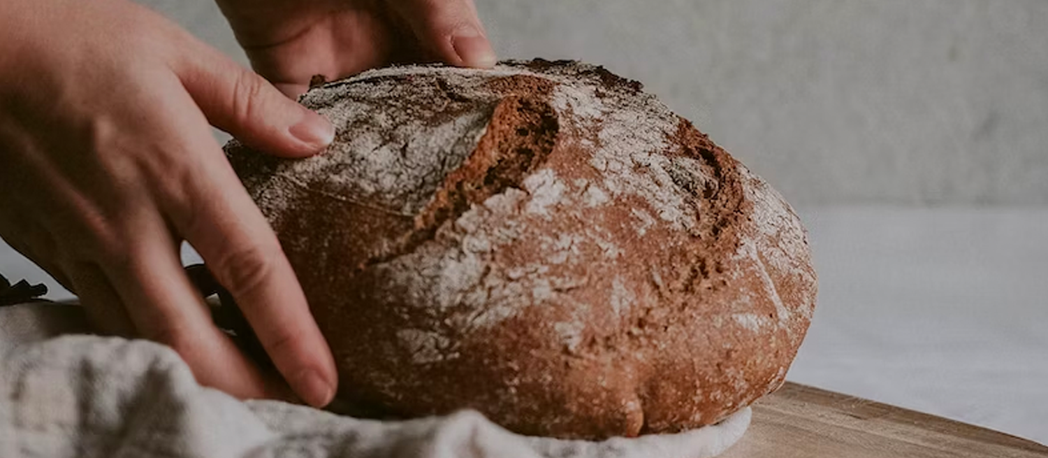 Hands picking up a loaf of sourdough bread from the counter